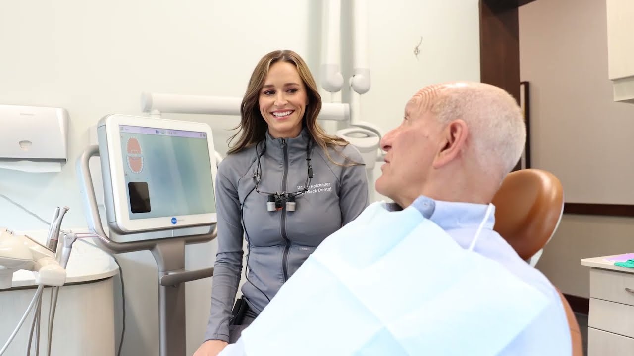 Doctor Liz laughing with senior man in dental chair