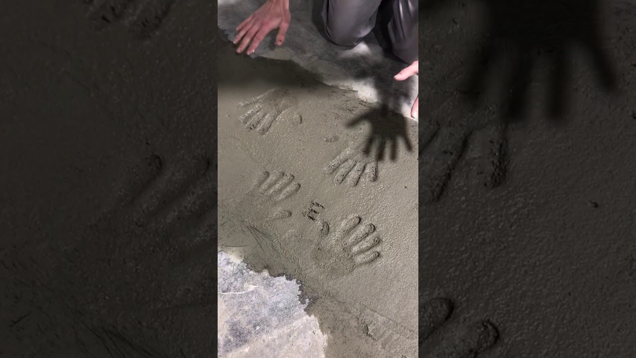 Josh putting his hand prints in cement flooring poured for the new showroom - J Thomas Home