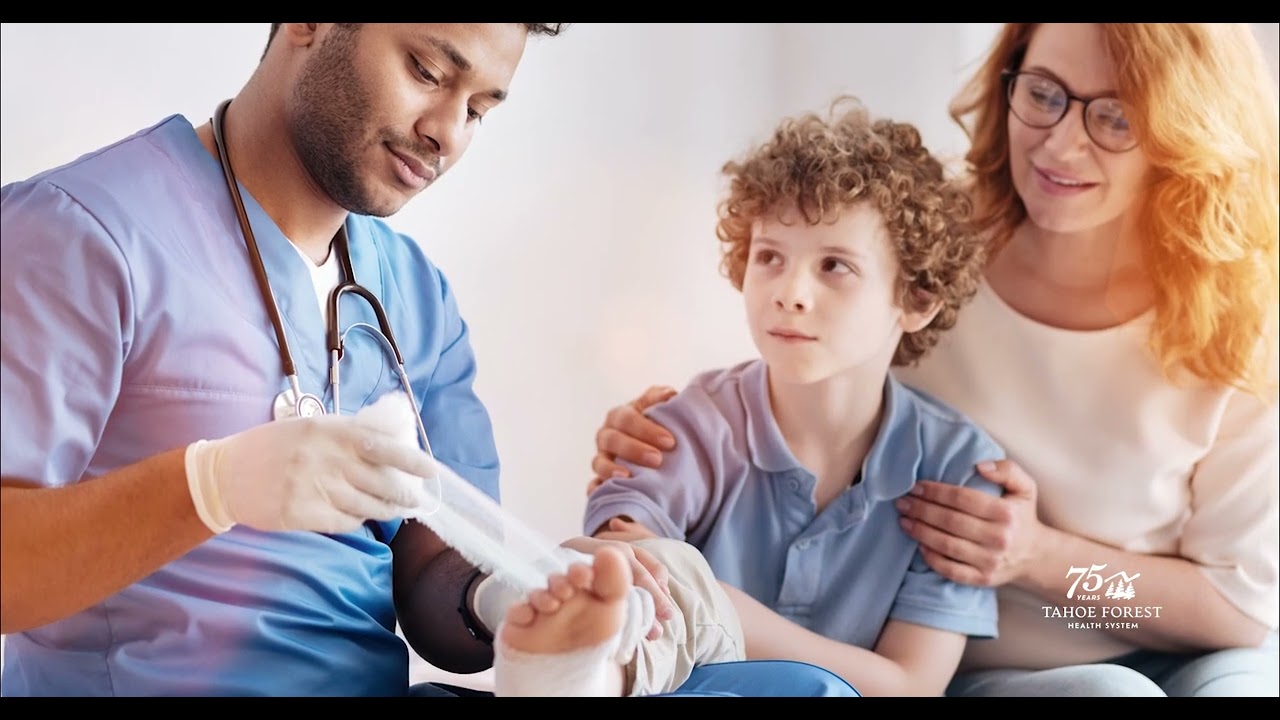 Physician wrapping a young boy's ankle while his mother hugs him