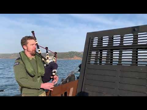 Bagpipe serenade on landing craft as troops and equipment offloaded from RFA Lyme Bay