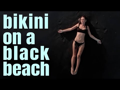 Cute girl in swimsuit - lies on a black beach - Sea waves - Summer time