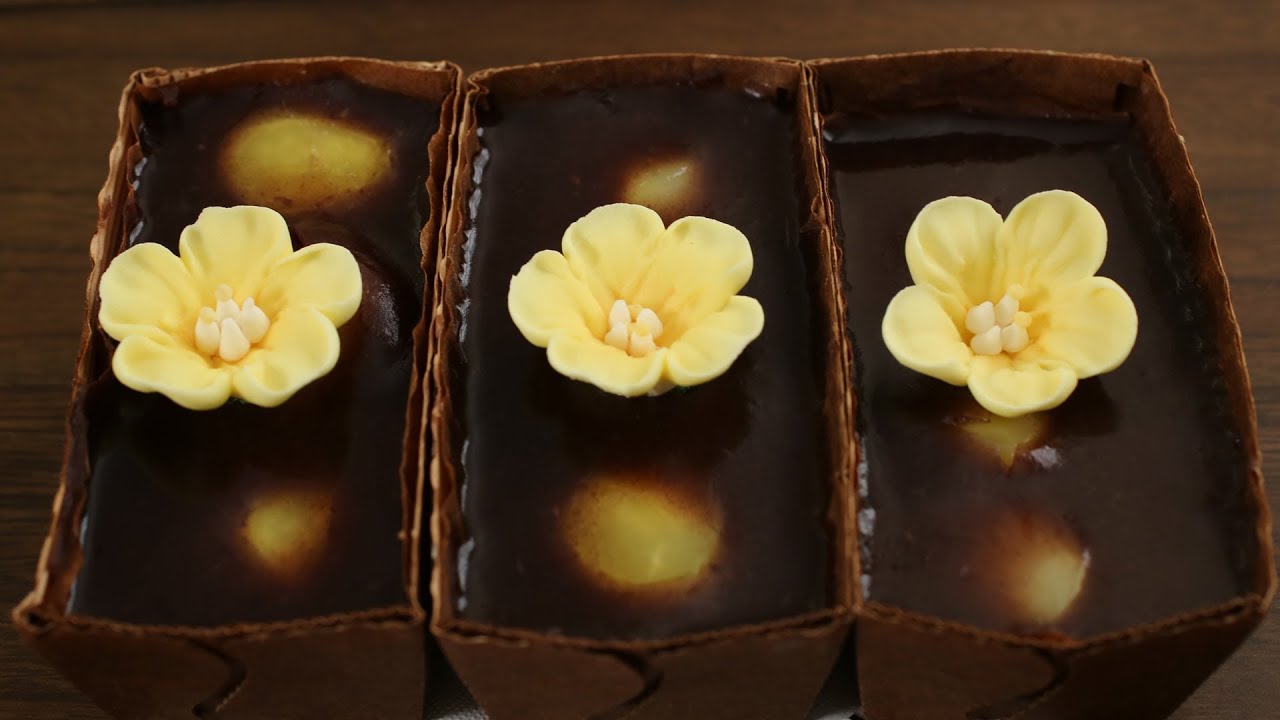 A plate of Korean yanggaeng red bean jelly cut into rectangular slices with smooth dark red color and a glossy finish from agar gel
