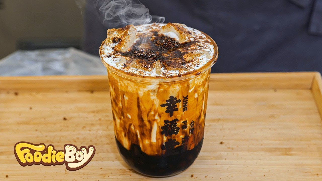 A Korean street vendor preparing a brown sugar boba milk drink at a stall in Daegu pouring caramel syrup over pearls in a clear cup