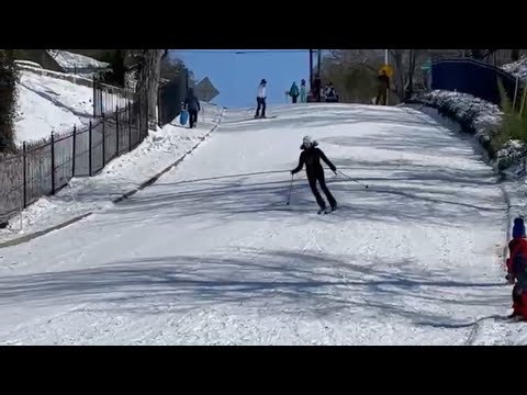 Watch people downhill ski, sled on Fort Worth road