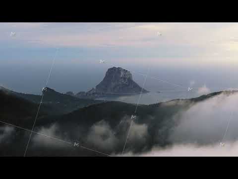 Aerial view of island of Es Vedra in Ibiza, Balearic Islands, Spain. Mountains covered by low clouds