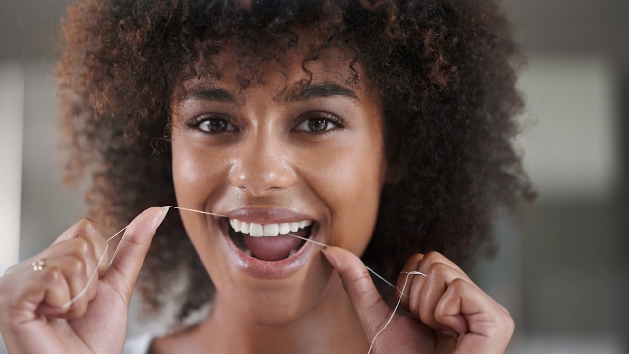 Smiling woman flossing her teeth