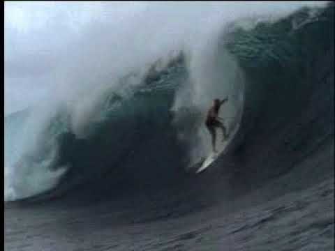 Trailer still: 16mm surf silhouettes, sun flares, and a skiff pushing toward a reef pass