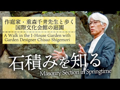 屋外のリビングスペース、屋根付きテラス、石造りの暖炉、大きな籐のソファ、屋外の敷物