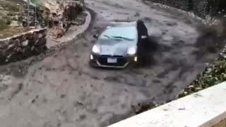 Car Speeds Down Road Trying To Escape Fast Moving River of Mud