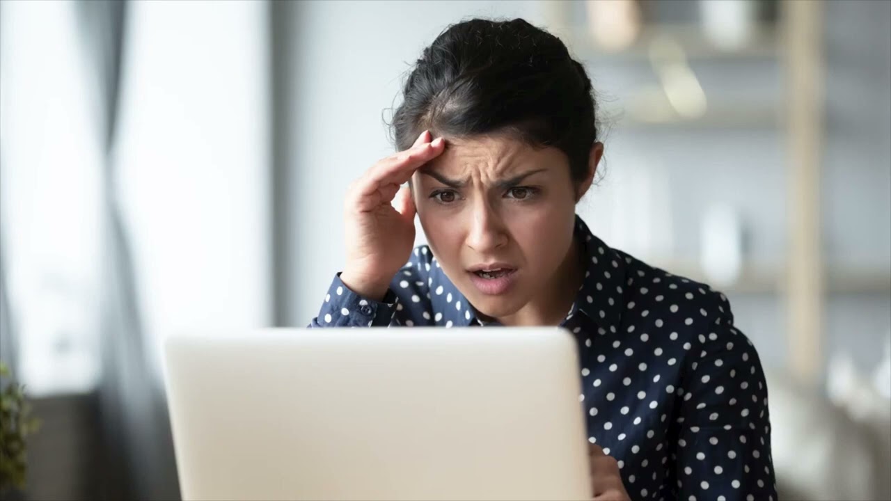 Een vrouw zit, zichtbaar in paniek, achter haar laptop.