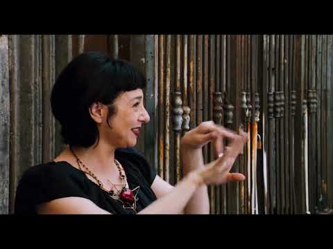 Passione trailer still: John Turturro wandering Naples with street musicians in warm evening light