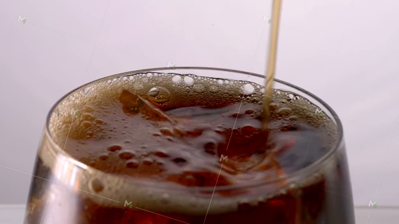 Pouring Cola with ice cubes. Cola with Ice and bubbles in glass.
