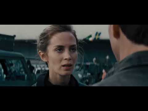 Edge of Tomorrow official trailer frame: exo-suited soldiers sprint through shrapnel as alarms wail