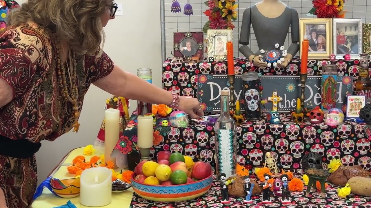 Board Member, Carol Jenkins, includes additional photos of her loved ones to the Ofrenda