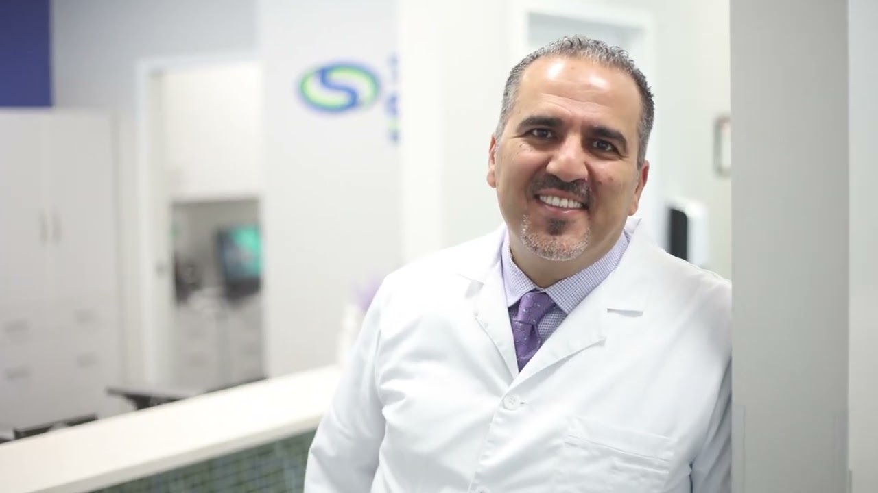 Doctor Alkhoury smiling in a white lab coat