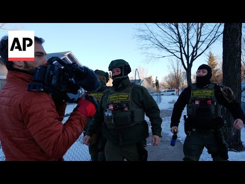 Federal officers push AP reporters back to their car as they document operation