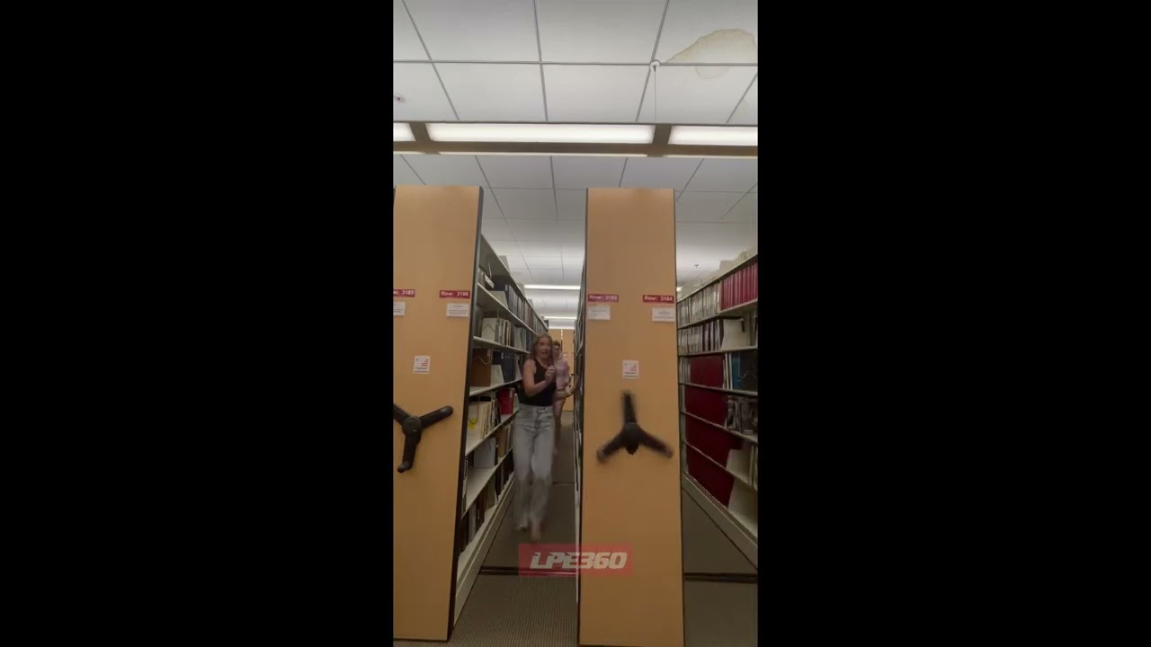 Women almost squeezed by library shelf