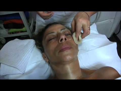 La ragazza fa una maschera di occhi Il massaggio al viso distante di rotazione affronta il pacco