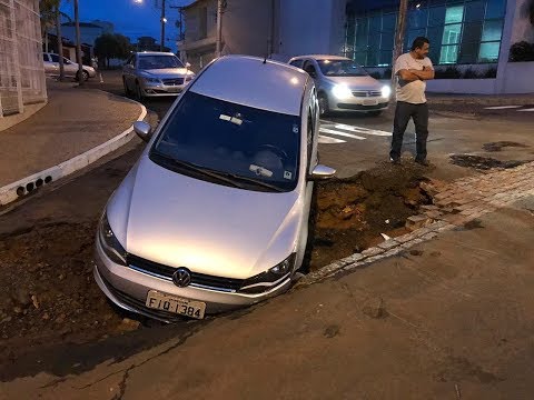 Motorista cai com o carro em buraco aberto pela chuva em obra inacabada