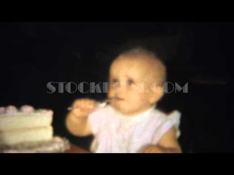 1963: Blonde baby girl eating half birthday cake with spoon.  AKRON, OHIO