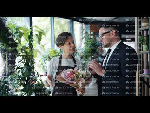 Female florist talking to male customer holding bunch of flowers in store