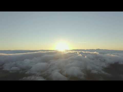 Le soleil se couche à l'horizon d'une chaîne de montagnes nuageuse