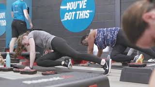 PureGym Buckingham: Gym with weightlifting racks, dumbbells, punching bags, turf area, weight plates, and digital timers.