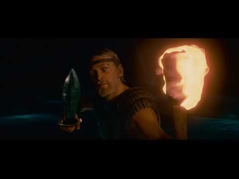 Close-up trailer frame: torchlit hall where the queen’s diegetic singing is set