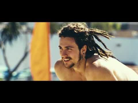 Savages trailer still — endgame nightfall over the Pacific, car lights threading a cliff road