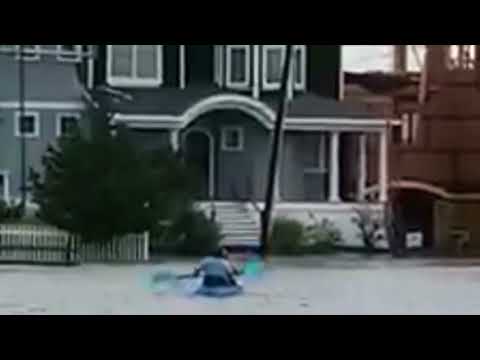 People kayak on a flooded street in Stone Harbor