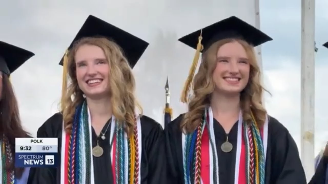 Twin sisters in their graduation caps and gowns side by side