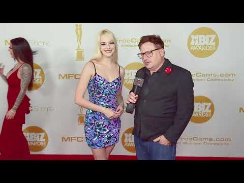 Kenna James in a flattering blue and purple dress on the red carpet at the Xbiz Awards in LA, CA.