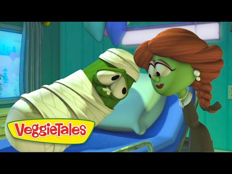 VeggieTales scene: a green mummy-like character wrapped in bandages on a hospital bed, leaning toward a woman with red braided hair.