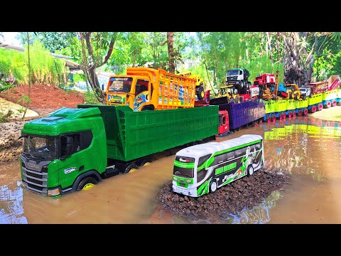 A long Scania truck unloads sand and finds a mobile bus, a fire truck, and a fire truck.