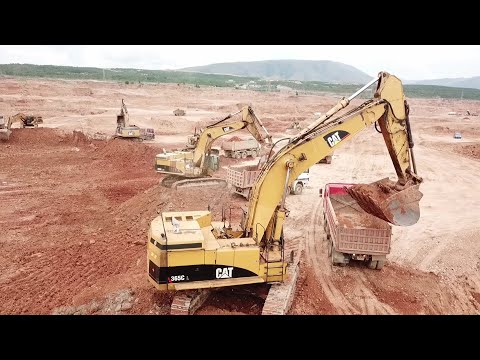 Five Caterpillar Excavators And A Fleet Of 4 Axle Trucks Working On A Huge Mining Area - Aerial View