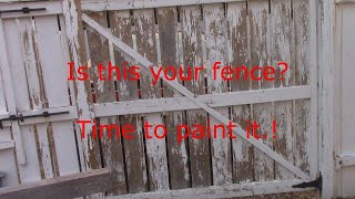 Painting a wooden fence with an airless sprayer.