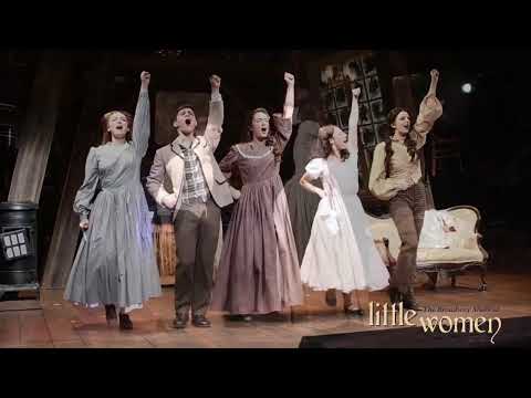 Promo still: Jo at her desk, pen paused, as a cadential figure resolves