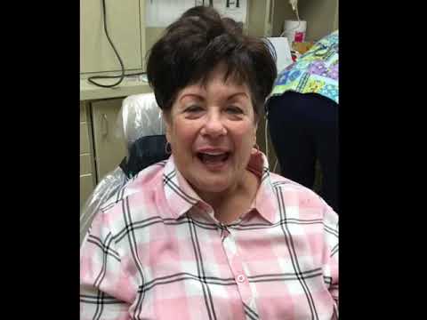 Woman in pink plaid shirt smiling in dental chair