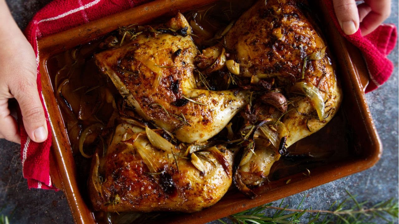 a tray of oven-baked chicken with some herbs and garlic garnish