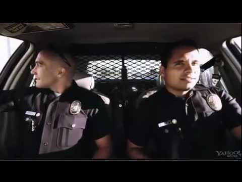 Trailer frame of Jake Gyllenhaal and Michael Peña in a patrol car, reflecting the film’s music-radio texture