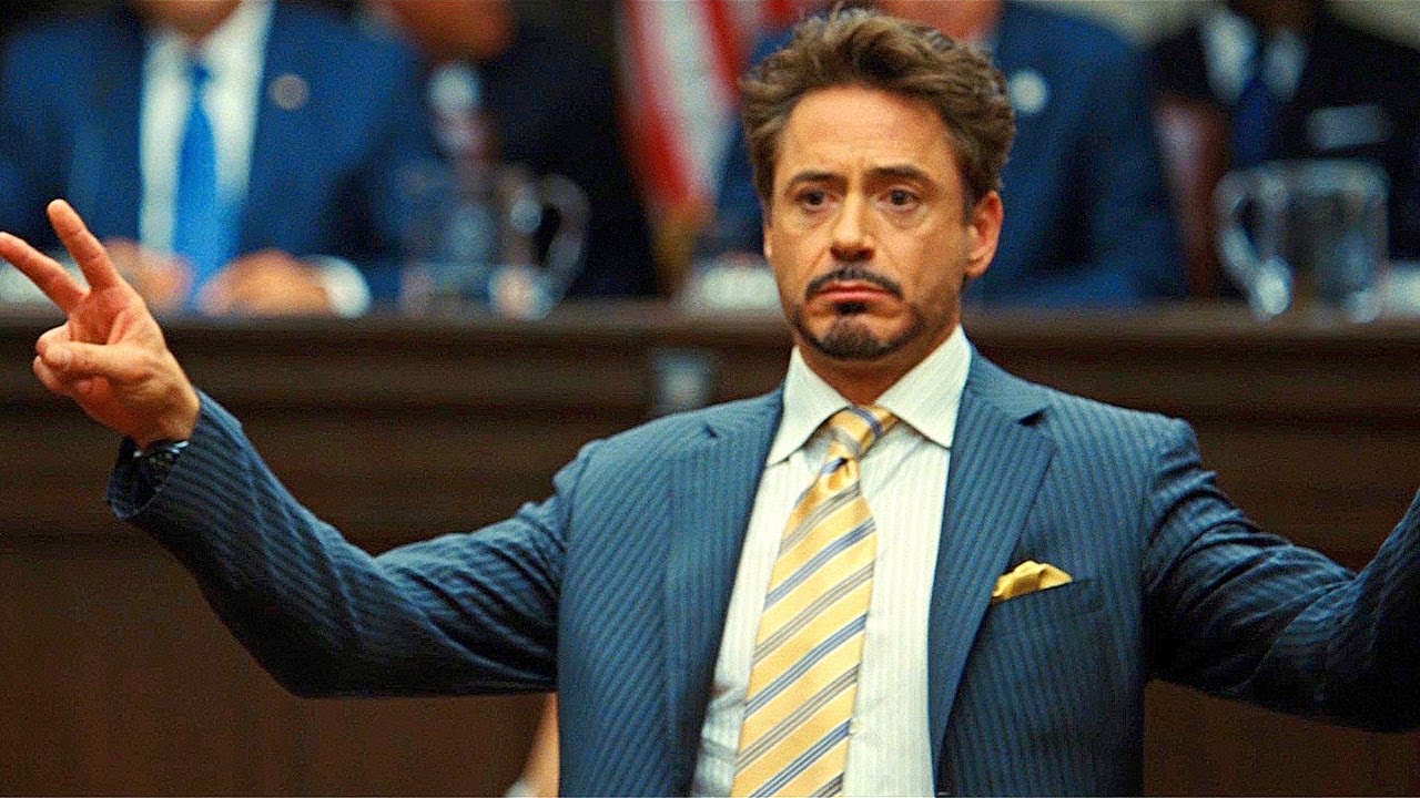 Iron Man 2 — Tony testifies before the Senate committee — completely relaxed, open, and expansive posture while the room demands deference