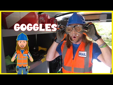 Person in a blue hard hat and orange safety vest wears clear protective goggles inside a workshop; the word 'GOGGLES' is overlaid.
