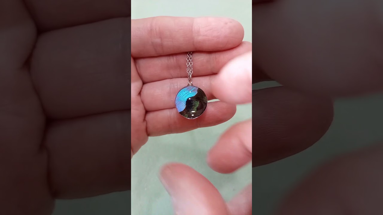 Collana da 18mm con vere ali di Blue Morpho e Papilio blumei sotto lente in vetro che mostra contrasto iridescente blu e verde