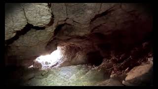 Condition report on the approach trail and cave mouth entrance. Video documents the descent required to reach the cave. Daylight visibility check for the first chamber; headlamps required beyond the entrance.