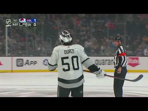 Sean Durzi backhands a shot through the wickets of Darcy Kuemper, puck stops short of  goal line.