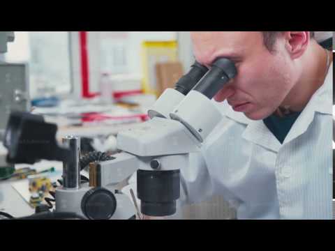 A worker checks a circuit board - Surface Mount Technology (Smt