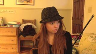 A woman with long hair and wearing a hat sitting in her bedroom.