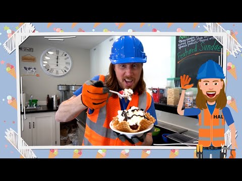 Man in blue hard hat and orange safety vest holds a waffle bowl topped with whipped cream and chocolate sauce in a cafe kitchen; a cartoon construction worker stands on the right.
