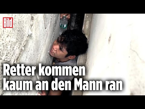 Mann steckt zwischen zwei Häusern fest