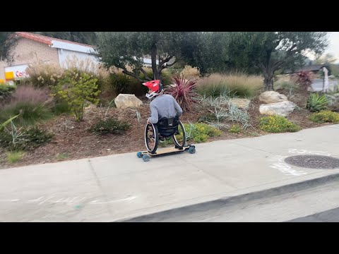 Evan Lalanne in his wheelchair riding an electric skateboard with traffic